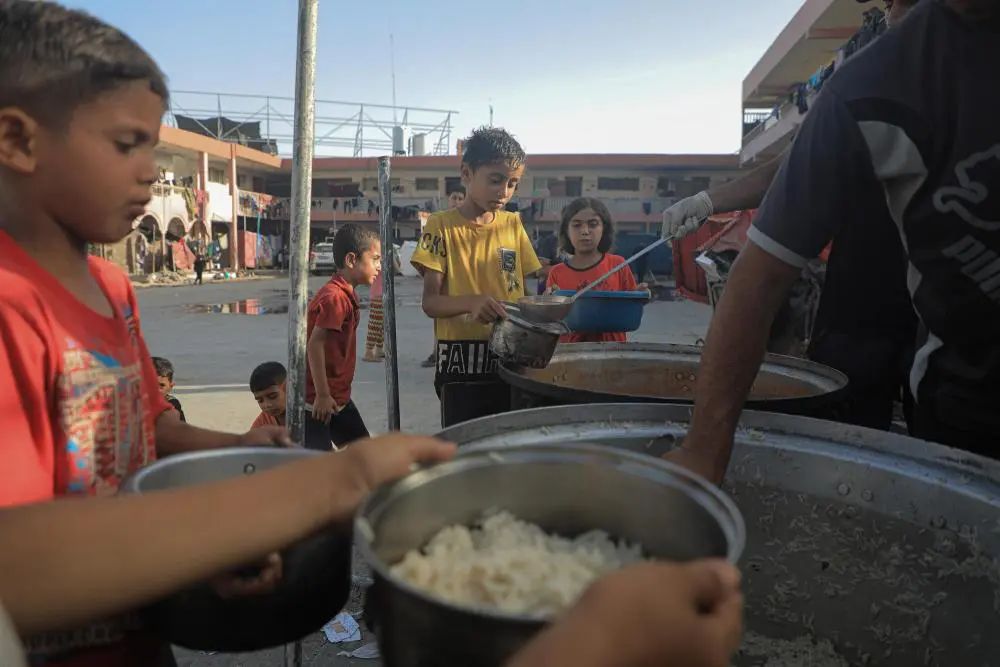 6月15日，在加沙地带南部城市汗尤尼斯，当地儿童领取救济食物。新华社发（里泽克·阿卜杜勒贾瓦德摄）